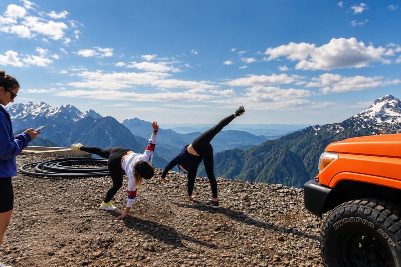 Guests stretching at a mountain viewpoint with snowy peaks during a jeep safari